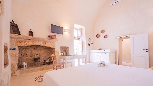 Ein Schlafzimmer mit Kamin aus Stein, einem Bett, einem Schreibtisch und einem Fernseher.