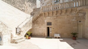 Ein Innenhof mit Steintreppe, einer Tür und Kübelpflanzen.