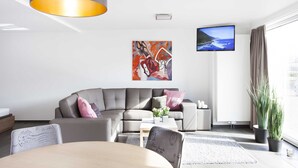 Una sala de estar moderna con un sofá gris, una mesa de centro y un televisor montado en la pared.