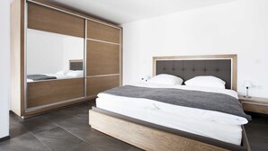 Un dormitorio con una cama, un armario y una mesita de noche.