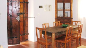 A dining area with a wooden table and chairs, a cabinet with glass doors, and a rustic door.