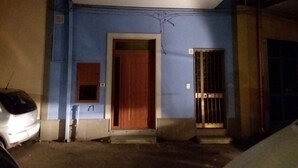 Ein Gebäude mit blauer Fassade, einer Holztür und einem schmiedeeisernen Gitter.