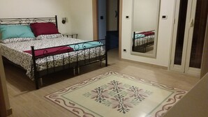 Ein Schlafzimmer mit einem Bett, einem Spiegel und einem gemusterten Teppich.