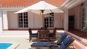A poolside area with wooden lounge chairs and a table under a large umbrella. - Villa with Books, Sun, Swing Bed, Private Pool And A Spacious Garden To Enjoy (Unknown)