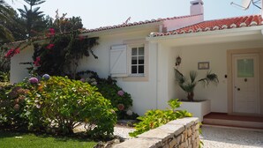 A house with a tiled roof, a stone wall, and a potted plant near the entrance. - Villa with Books, Sun, Swing Bed, Private Pool And A Spacious Garden To Enjoy (Unknown)