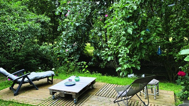 An outdoor patio with a wooden table, two lounge chairs, and a small table. - Large bedroom above an artist's studio (Triguères)