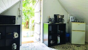 A small kitchen with a microwave, coffee maker, and refrigerator. There is a door leading to a garden. - Large bedroom above an artist's studio (Triguères)