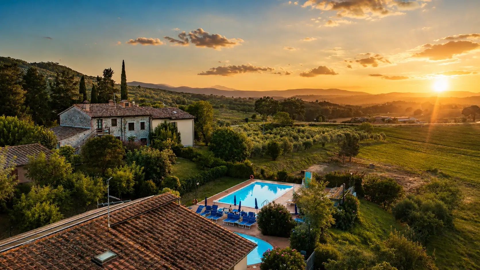 A residential property with a swimming pool, surrounded by lush greenery and hills.
