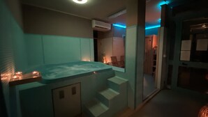 Ett spaområde med ett bubbelbad, trappsteg som leder upp till det, och ett litet, avskilt utrymme med en dörr.