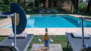 A poolside area with lounge chairs and a table with a bottle and glasses. - The Real Tuscany great for families and friends. (Buonconvento, Siena)