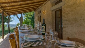 A long dining table set outdoors with a view of the countryside. - The Real Tuscany great for families and friends. (Buonconvento, Siena)
