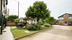 A courtyard with a covered seating area, a small building, and a large tree. - Apartment in farmhouse, Venice. Bedroom, bathroom, full kitchen / living room. (Oriago)