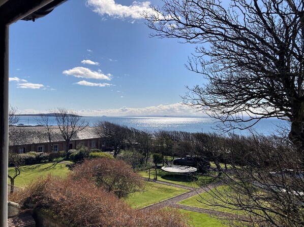 A view of a coastal landscape with a clear sky, a body of water, and a grassy area with a circular structure. - Cardy Cottage sleeps 4, pet friendly, sea views near St Andrews (Lower Largo)