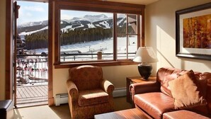 A cozy living room with a view of a snowy mountain landscape through large windows. - Grand Lodge @ Peak 7, Spring Break, Mar 21-28 2026 only, 2 BR condo - sleeps 8 (Breckenridge)