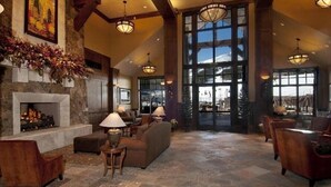 A spacious lobby with a fireplace, comfortable seating, and large windows offering a view of the outdoors. - Grand Lodge @ Peak 7, Spring Break, Mar 21-28 2026 only, 2 BR condo - sleeps 8 (Breckenridge)