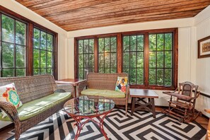 A sunroom with wicker furniture, a glass coffee table, and a chevron-patterned rug. - Historic charm in downtown Tryon; 18 Minutes from Tryon Intl Equestrian Center (Tryon)