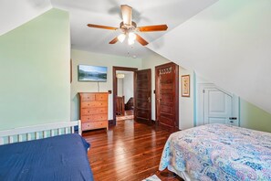 A bedroom with a ceiling fan, a bed with a patterned bedspread, a dresser, and a door leading to another room. - Historic charm in downtown Tryon; 18 Minutes from Tryon Intl Equestrian Center (Tryon)