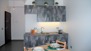 Una cocina compacta con armarios grises, un lavamanos y una zona de comedor con una mesa y sillas.