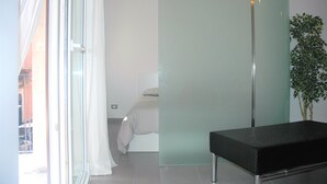 Una habitación de hotel moderna con una cama, un banco y una planta en maceta.