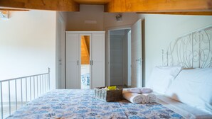 Una camera da letto con un letto, un comodino, un cesto e una porta che dà su un'altra stanza.