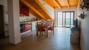 Un'ampia cucina con travi in legno, una zona pranzo con sedie rosse e una vista tramite un'ampia porta scorrevole.