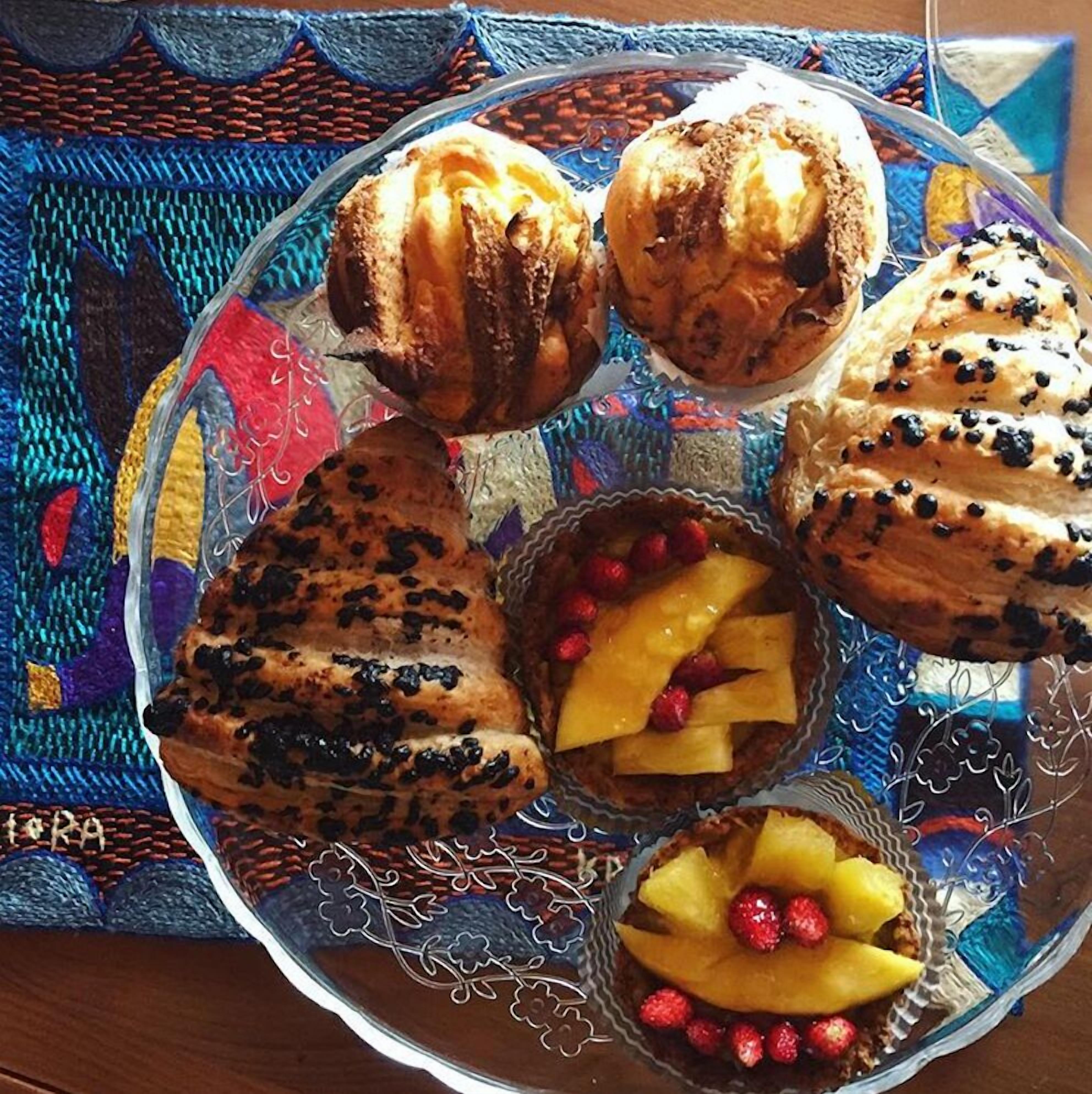 Un piatto con una varietà di pasticcini e dolci su una tovaglia fantasia.