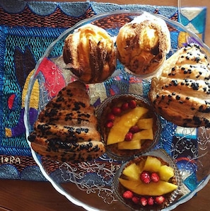 A plate of assorted pastries and desserts on a patterned tablecloth. - The sea in the attic  (agropoli)