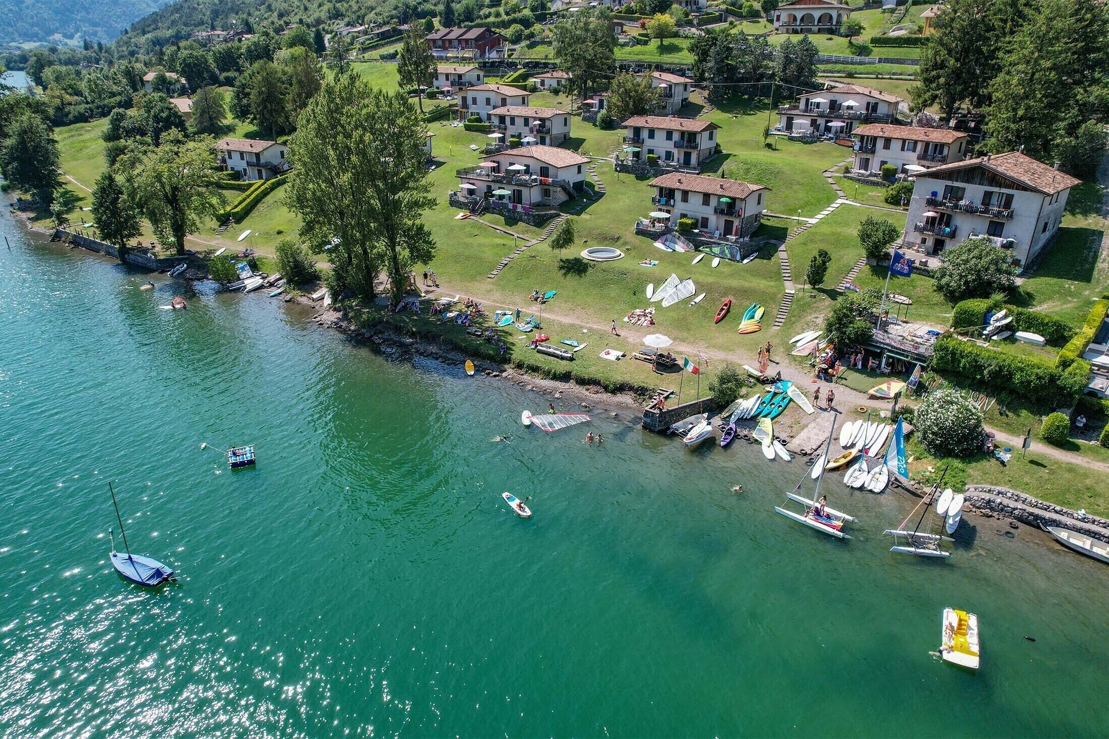 A lakeside property with multiple buildings, boats, and a well-maintained lawn.