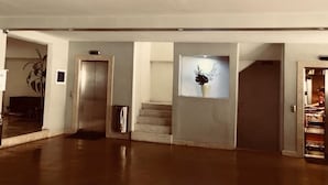 A spacious lobby with a central staircase, an elevator, and a wall-mounted display. - Elegante Apto en Polanco c-Terraza (Mexico City)