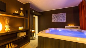 A spa room with a hot tub, shelves with candles, and a wall-mounted artwork.