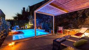 A pool area with lounge chairs and a pergola.