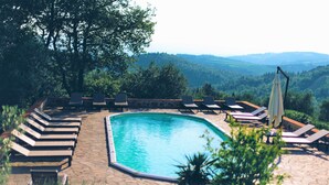 A pool area with lounge chairs and a view of the surrounding landscape.