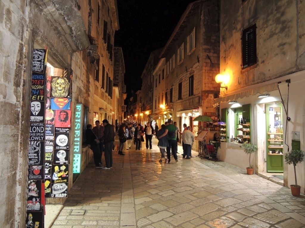 A narrow street lined with shops and a row of stickers on a wall.