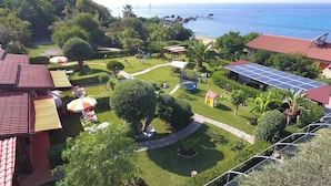 A garden with a pool, a small house, and solar panels. - Deluxe three-room apartments - at Le Casette sul Mare (Capo Vaticano)