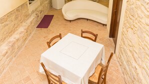 A dining area with a table and chairs, a stone wall, and a small white cabinet.