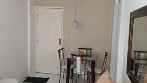 Ett rum med en soffa, ett matbord med stolar, en dörr och en hängande lampa.