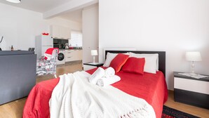 A modern hotel room with a neatly made bed, a dining area, and a kitchen in the background. - Apartment Anny1magnificant views over the ocean, mountains and banana plantation (Madeira)