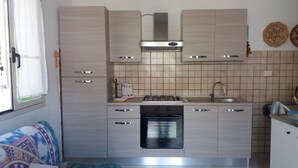 A compact kitchen with a stove, oven, and sink. - House 2 rooms +Garden, barbecue, children max 11 years free, in Costa Verde.  (Fluminimaggiore)