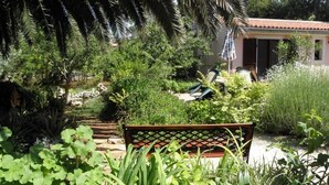 Um jardim com um banco, um caminho e um edifício com telhado de azulejos.