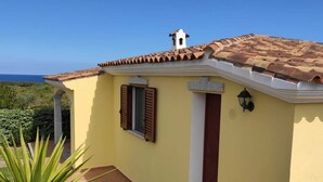 Un bâtiment jaune avec un toit en tuiles, un clocher et une porte à volets.