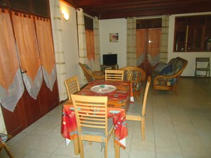 A dining area with a table set for four, surrounded by wooden chairs with colorful cushions.