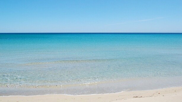 Ein Strand mit klarem türkisfarbenem Wasser und einem Sandufer.