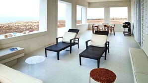 Ein geräumiger Raum mit großen Fenstern, einem Essbereich und einer Sitzecke mit Lounge-Stühlen und einem Sofa.