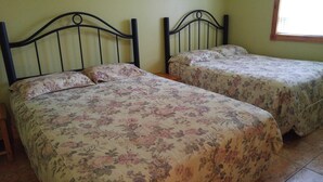 Two twin beds with floral bedding, a wooden headboard, and a window with a view. - Suites of Wasaga - Beach Area 1 (Wasaga Beach)