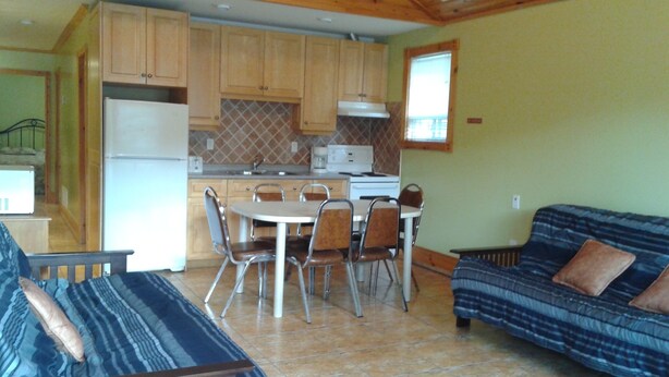A compact living space with a kitchenette, dining area, and a sofa. - Suites of Wasaga - Beach Area 1 (Wasaga Beach)