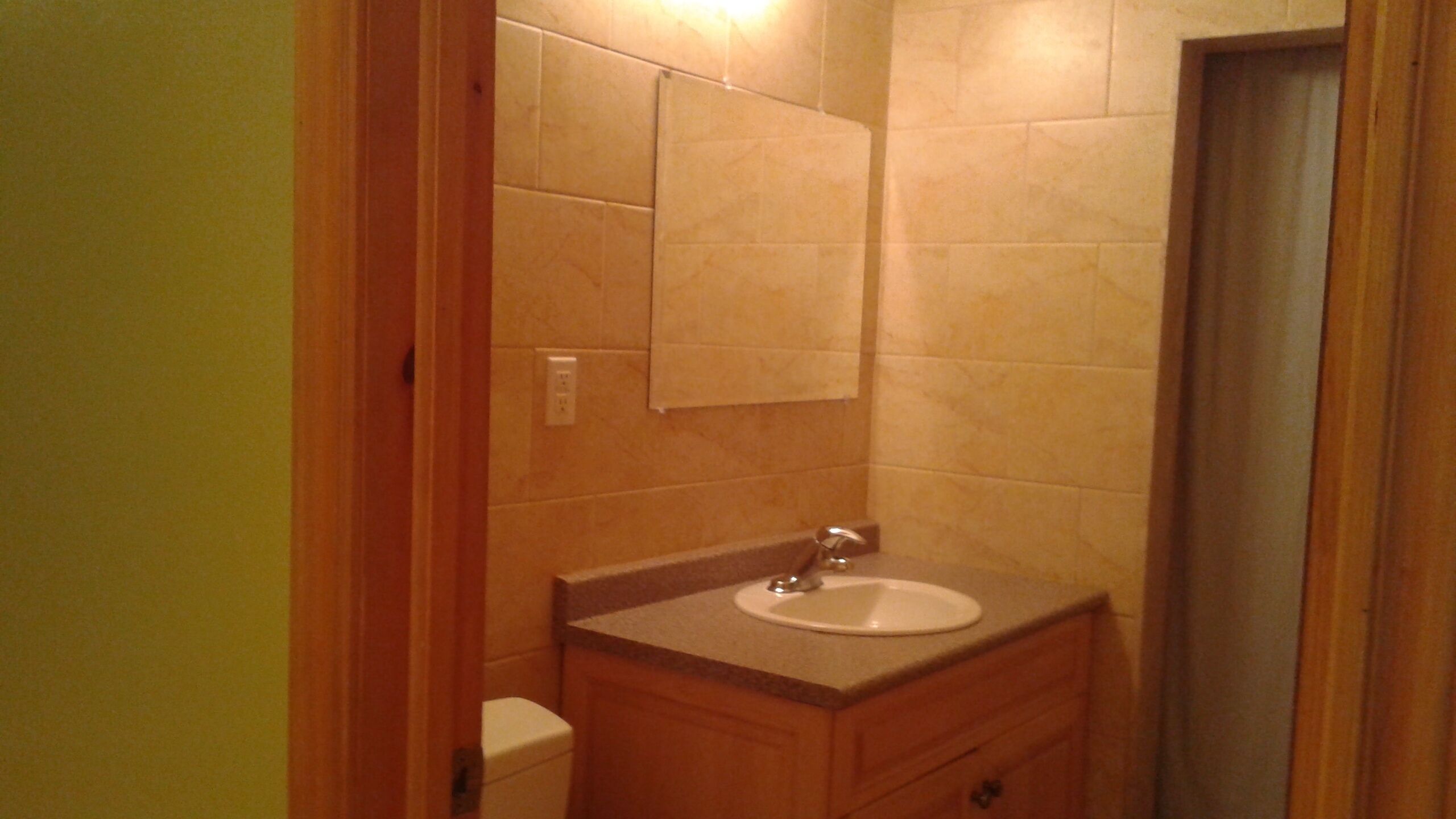A bathroom with a sink, mirror, and wooden cabinet.