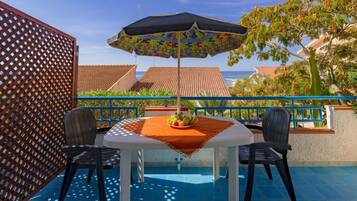 Un balcon avec une table, des chaises et un parasol.
