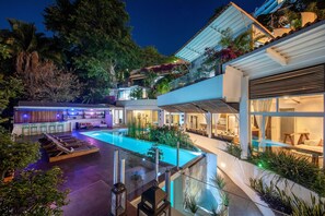 A modern house with a swimming pool, outdoor seating, and lush landscaping. - Nemi Eco Villa (Puerto Vallarta)