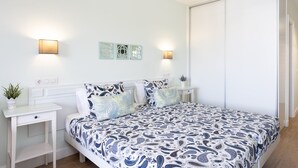 Un dormitorio con cama, mesitas de noche, apliques en la pared y un ventilador de techo.