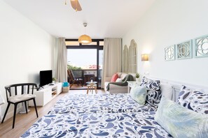 Een slaapkamer met een groot bed, een televisie, een bureau en een balkon met uitzicht.